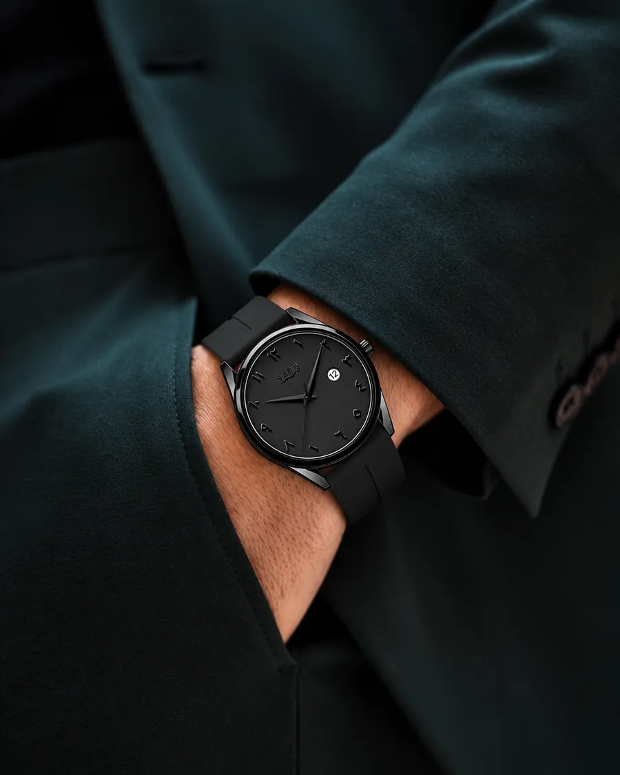 Matte black unisex watch worn with a dark tailored suit